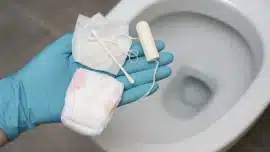 Clean, modern bathroom with a white toilet and tiled walls, representing proper plumbing care and sewer system maintenance.